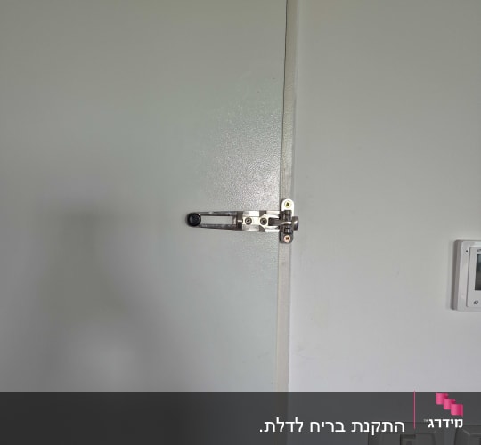 מנעול דלת עם בריח מתכת על דלת לבנה